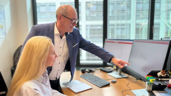 Mitarbeiter erklärt Mitarbeiterin etwas am PC