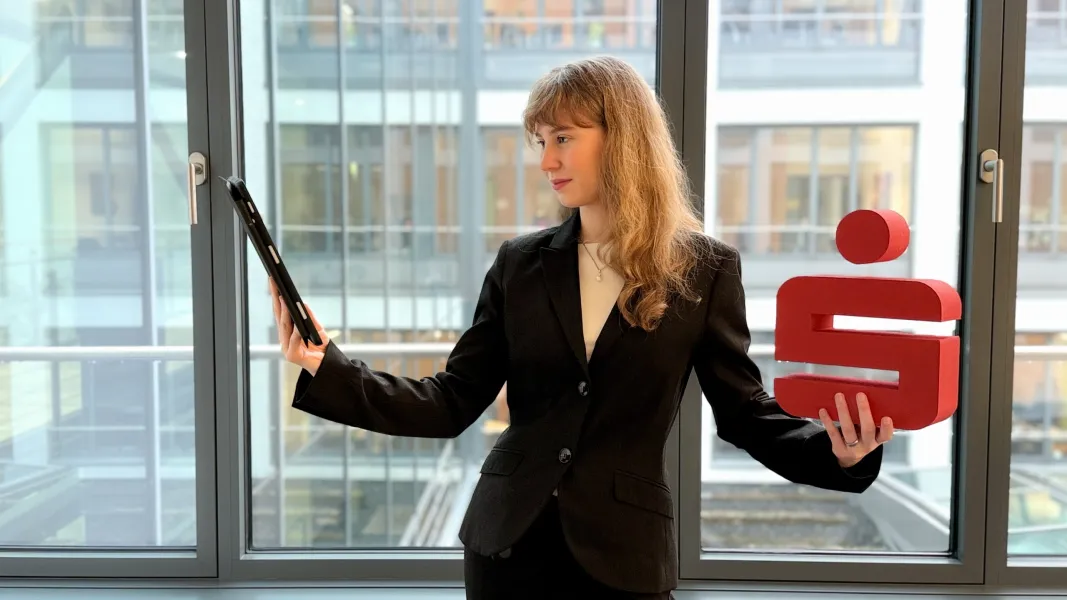 Unsere Duale Studentin hält rechts ein IPad in der Hand und links ein Sparkassen-Symbol