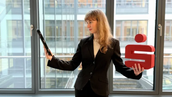 Unsere Duale Studentin hält rechts ein IPad in der Hand und links ein Sparkassen-Symbol